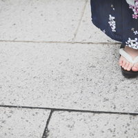 赤い鼻緒の下駄を履いた浴衣姿の女性の足元の写真