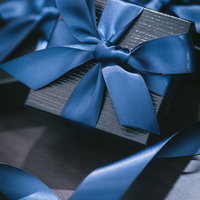 グレーの包装紙に青いリボンが巻かれたプレゼントの写真