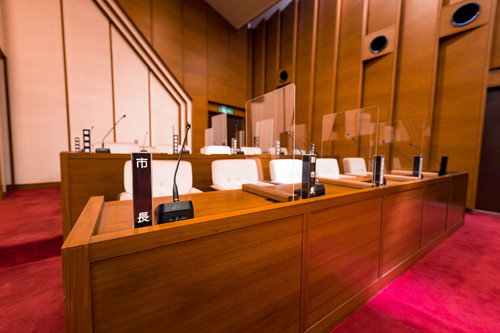 津山市議会の理事者席に並ぶ市長席、副市長席と議員席