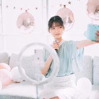 パステルカラーの風船に囲まれて配信する自撮り女子の写真