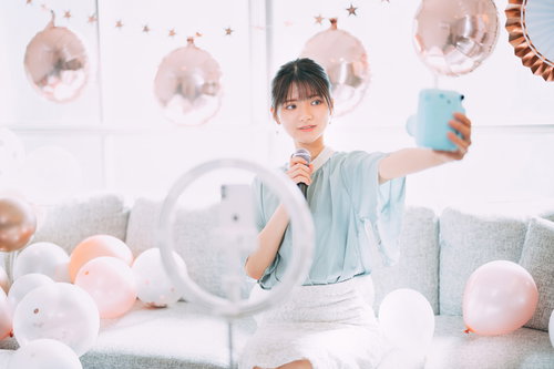 パステルカラーの風船に囲まれて配信する自撮り女子