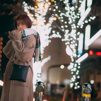 ライトアップした駅前で待ち合わせするコートの彼女の写真