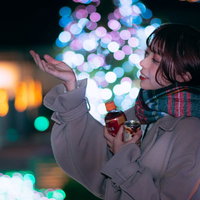 イルミネーションの玉ボケをバックに手を上げて喜ぶ彼女の写真
