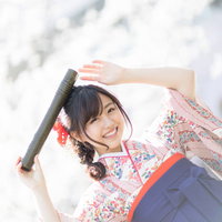 卒業証書の丸筒を持って喜ぶ桜柄の袴姿の女子大生の写真