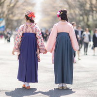 卒業式に2人で手をつなぎ歩く袴姿の女性の後ろ姿の写真