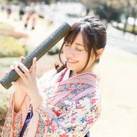 大学生活を思い返す卒業女子、花柄の着物と紫の袴で卒業証書を手に掲げた晴れ姿の写真