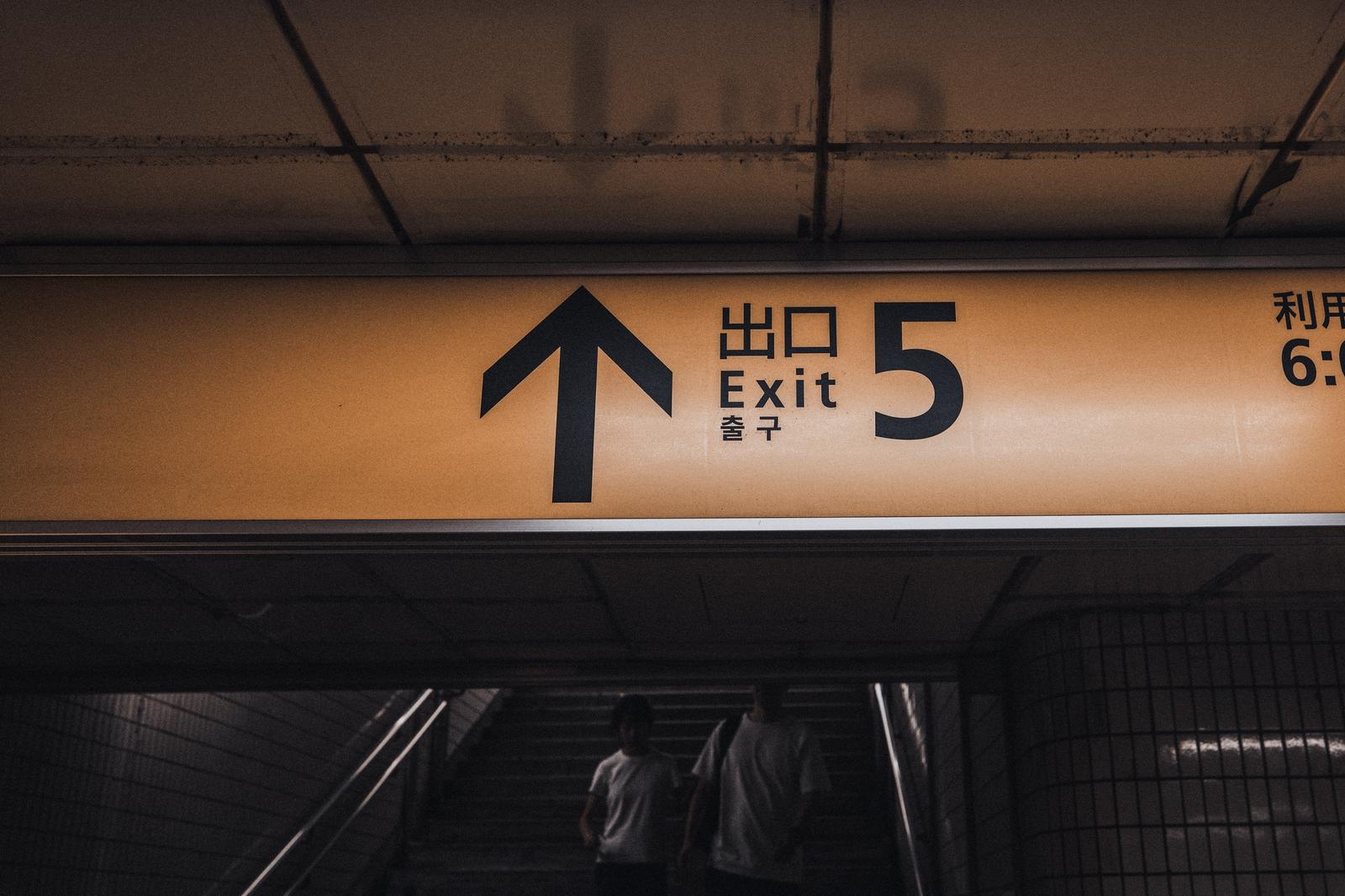 地下鉄駅のオレンジ色の案内板に5番出口の表示と上向き矢印