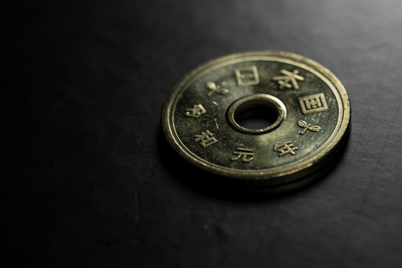 中央に四角い孔が開いた銀色の5円玉硬貨をクローズアップで撮影した写真