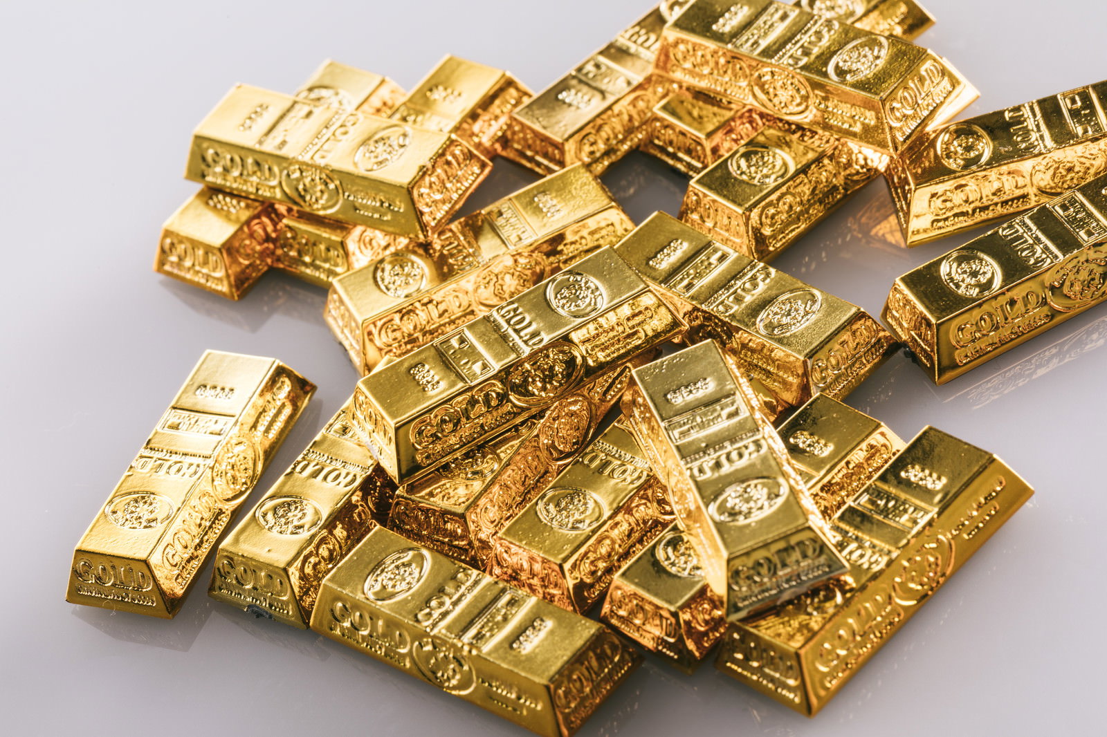 光沢のある黄金色のゴールドバー（金塊）が複数積み重なっている