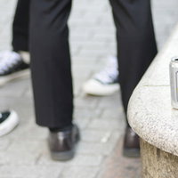 飲み捨てられた缶ビールと人々の足元の写真