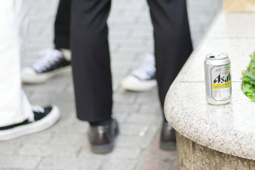 飲み捨てられた缶ビールと人々の足元