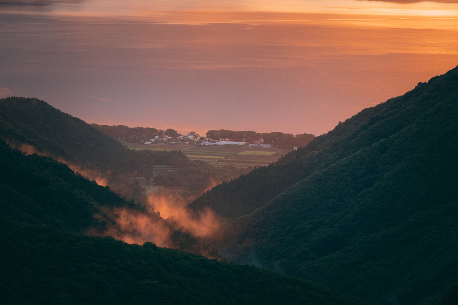 夕焼け空の下、御霊櫃峠から見た山間部の渓谷と雲海、遠方に猪苗代湖方面の景色