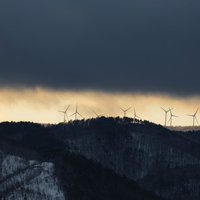 冬の山並みに立ち並ぶ風力発電の風車群と雪景色の写真