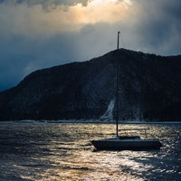 猪苗代湖に停泊するセーリング船と雪化粧の山々の写真