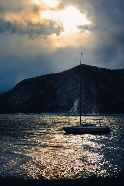 猪苗代湖に停泊するセーリング船と雪化粧の山々