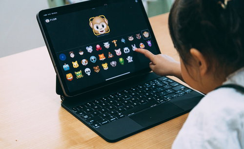 iPadのアニ文字アイコンを選んでタッチする女児の後ろ姿