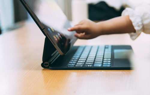 iPad Proの画面に触れる子どもの手と黒いキーボード付きケース