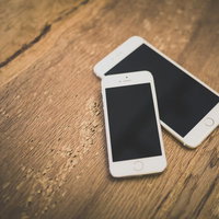 機種違いのスマートフォン2台を並べた木製テーブルの写真