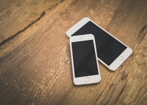 機種違いのスマートフォン2台を並べた木製テーブル