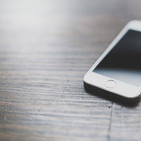 木目のテーブルに置かれたスマートフォンの写真