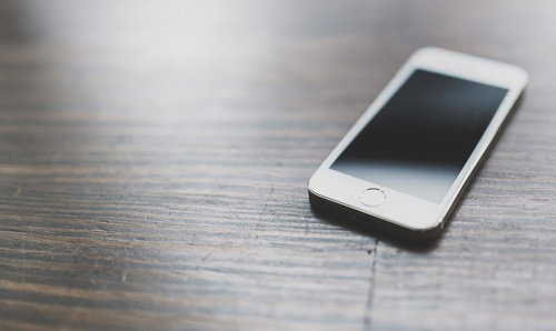 木目のテーブルに置かれたスマートフォン