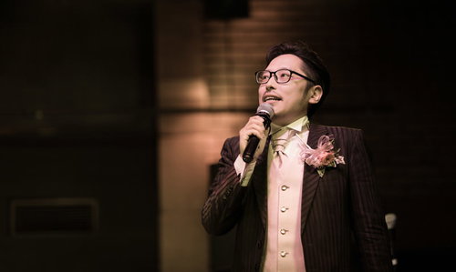 マイクを握る司会兼主役の新郎がスピーチをする結婚式の