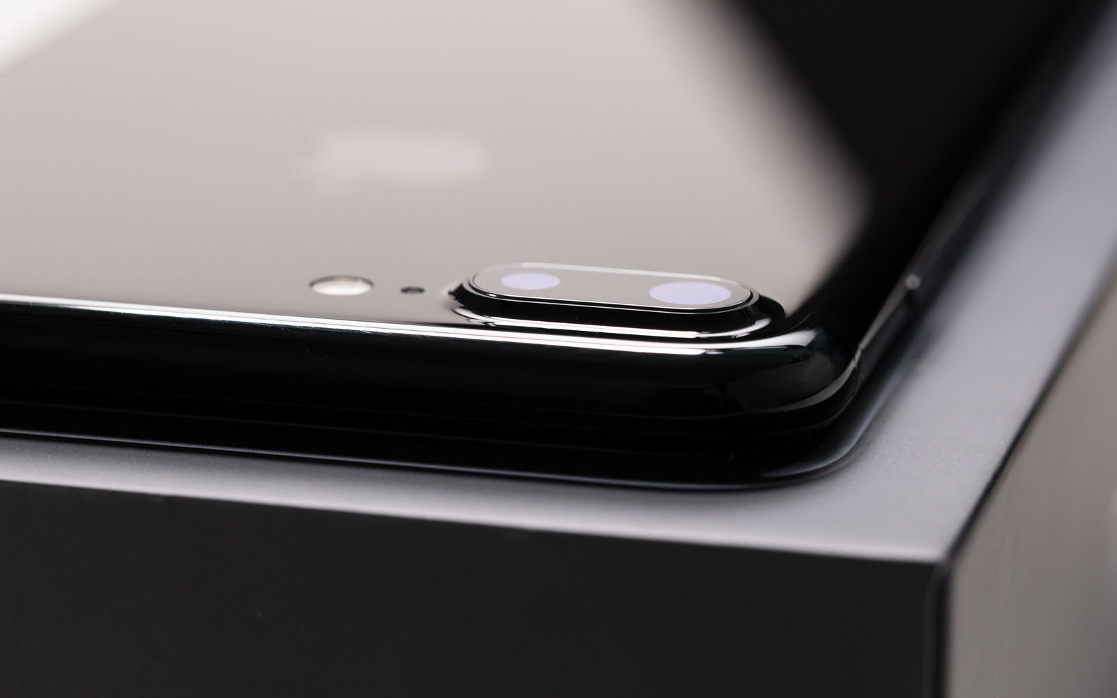 箱の上に置かれた黒いスマートフォンの背面カメラ