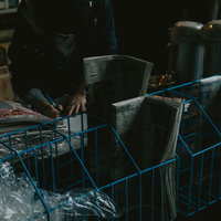 築地市場の薄暗い売店に並ぶ新聞や雑誌と積み重ねられた段ボール箱の写真