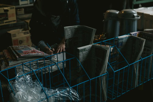 築地市場の薄暗い売店に並ぶ新聞や雑誌と積み重ねられた段ボール箱