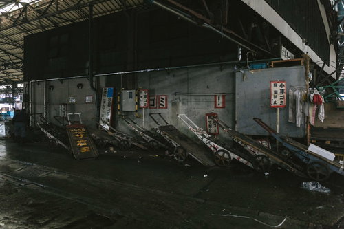 東京築地市場内に並ぶ老朽化した金属製台車の運搬風景