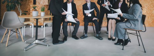 オープンスペースで資料を手に打ち合わせするプレゼンチーム