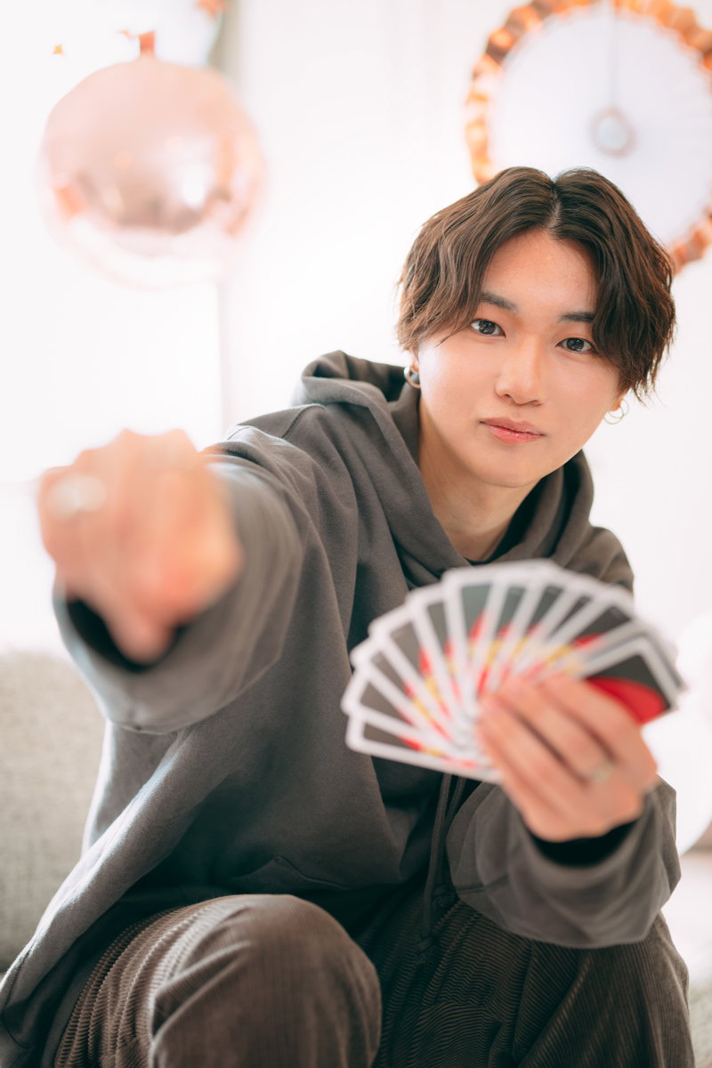 カードゲームを楽しみながら笑顔を見せる男性［モデル：SHUN］