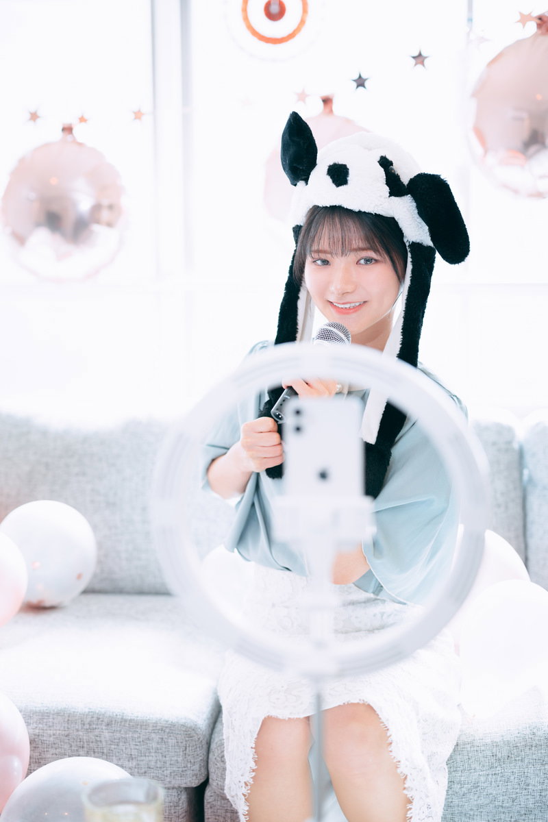 白いパンダキャップをかぶってスマートフォンで配信する女性［モデル：モデルリリース］
