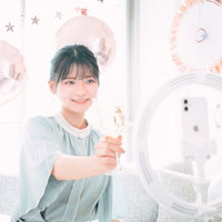 視聴者のみんなと乾杯する女性生主がシャンパングラスを掲げたシーンの写真