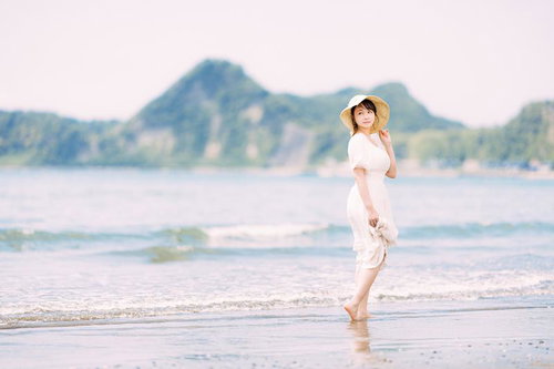 白いワンピース姿で波打ち際を歩く彼女の夏ポートレート