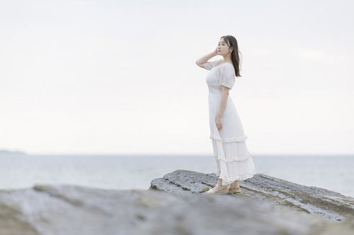 沖ノ島の岩礁でポートレート撮影する白いワンピースの女性