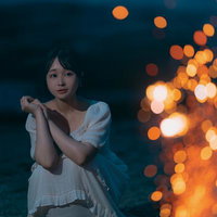 砂浜で夜間に手持ち花火を楽しむ女性のポートレートの写真