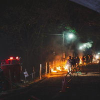 夜間の松明あかしで炎を掲げて歩く参列者たちの写真