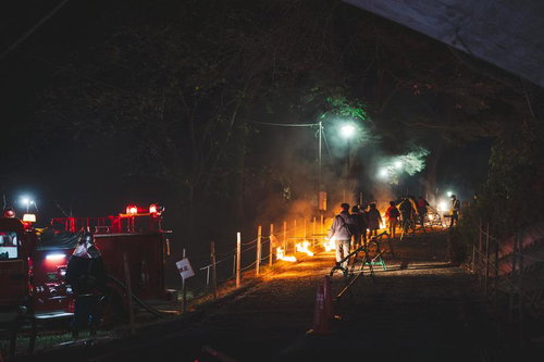 夜間の松明あかしで炎を掲げて歩く参列者たち