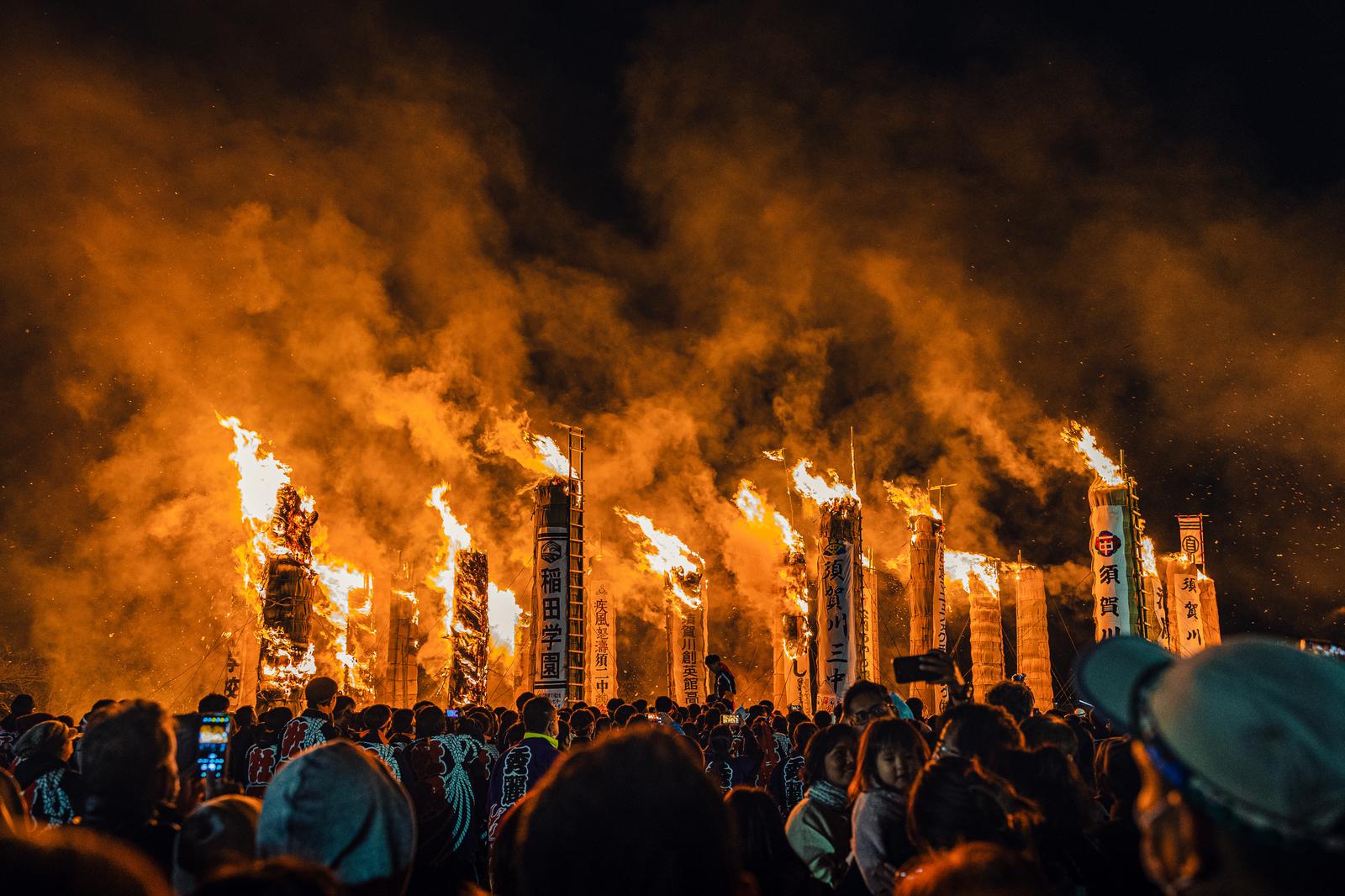 Large torches burning, with flames and smoke rising as spectators watch the Sukagawa City fire festival