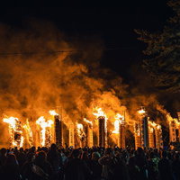 大松明から立ち上がる煙を纏う火祭りの炎の写真