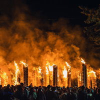 燃え上がる大松明の炎を見つめる観客たちの写真