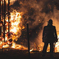 激しく燃え上がる松明の火柱と消防隊員のシルエットの写真