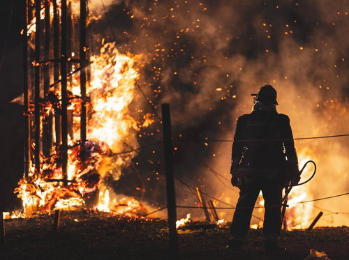 激しく燃え上がる松明の火柱と消防隊員のシルエット