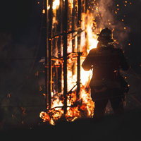 炎の光によって幻想的に浮かび上がる消防隊員のシルエットの写真