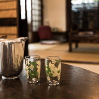 古い古民家の和室、ちゃぶ台に置かれた冷たい水とコップの写真