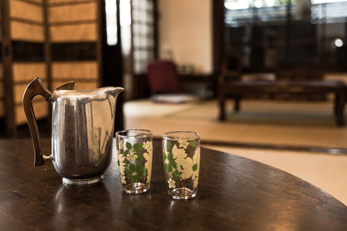 古い古民家の和室、ちゃぶ台に置かれた冷たい水とコップ