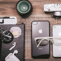 木目のテーブルに置かれたガジェット製品と白メガネの写真