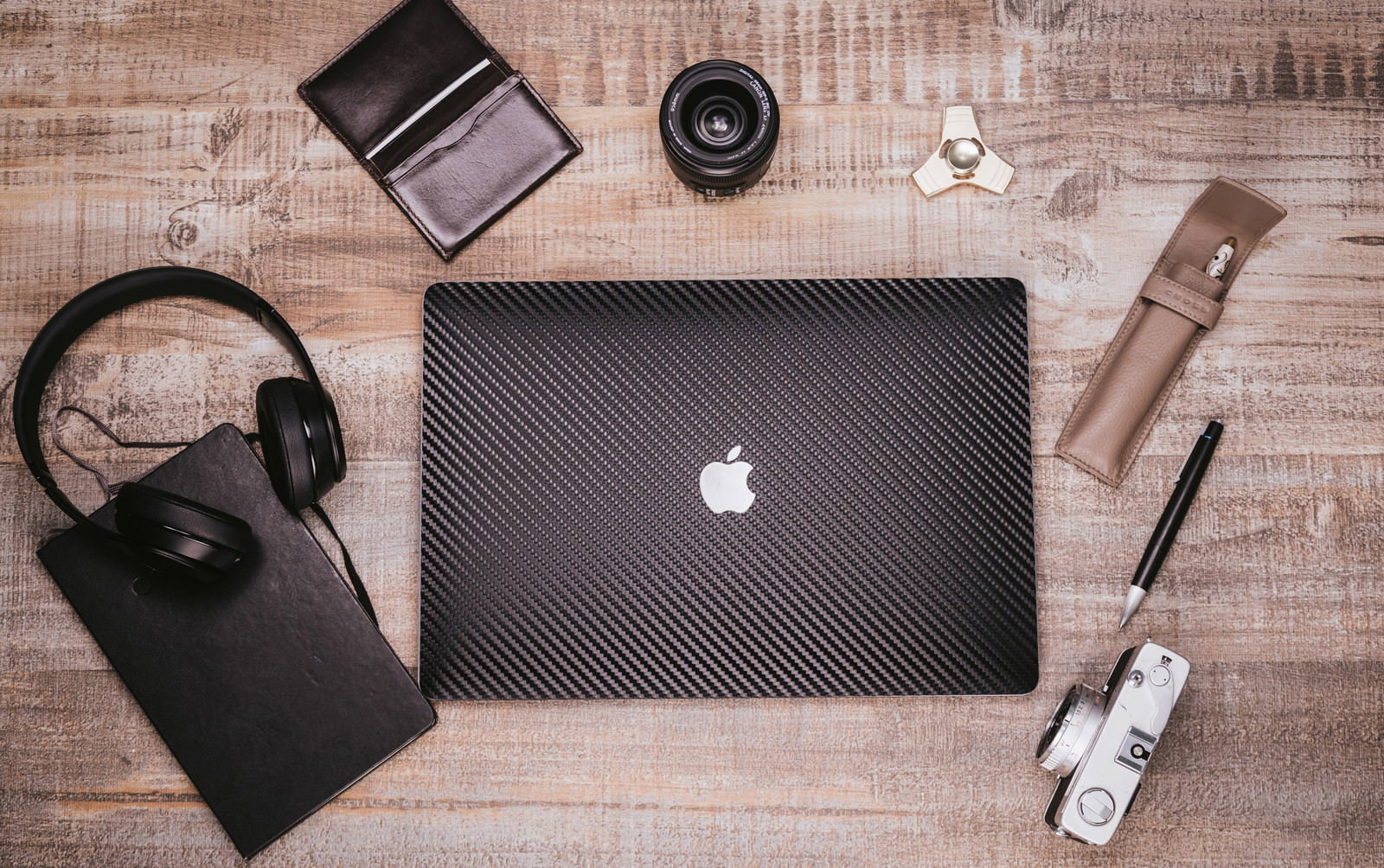 木目のデスクにMacBookとガジェットを並べた俯瞰写真