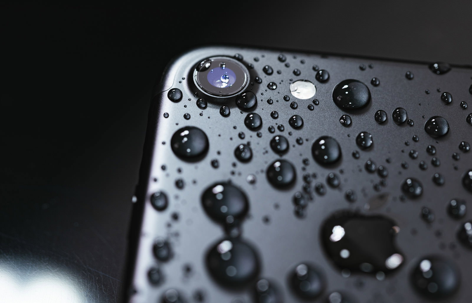 黒いiPhoneの表面に無数の水滴が付着している様子